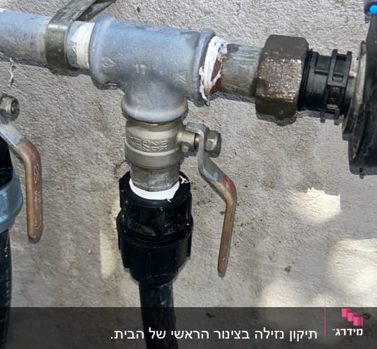 ברז מים עם צינור וחיבורים על קיר בטון